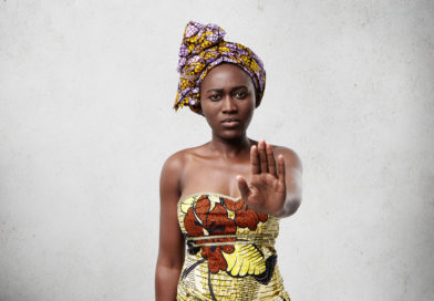 Stop it! African woman with dark smooth skin wearing traditional clothes showing her palm denying not to do something. Confident dark-skinned female showing no gesture. Veto and demand concept